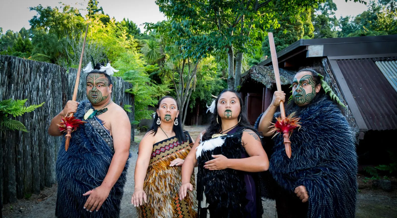 Mitai performers in korowai cloaks standing at the village palisade