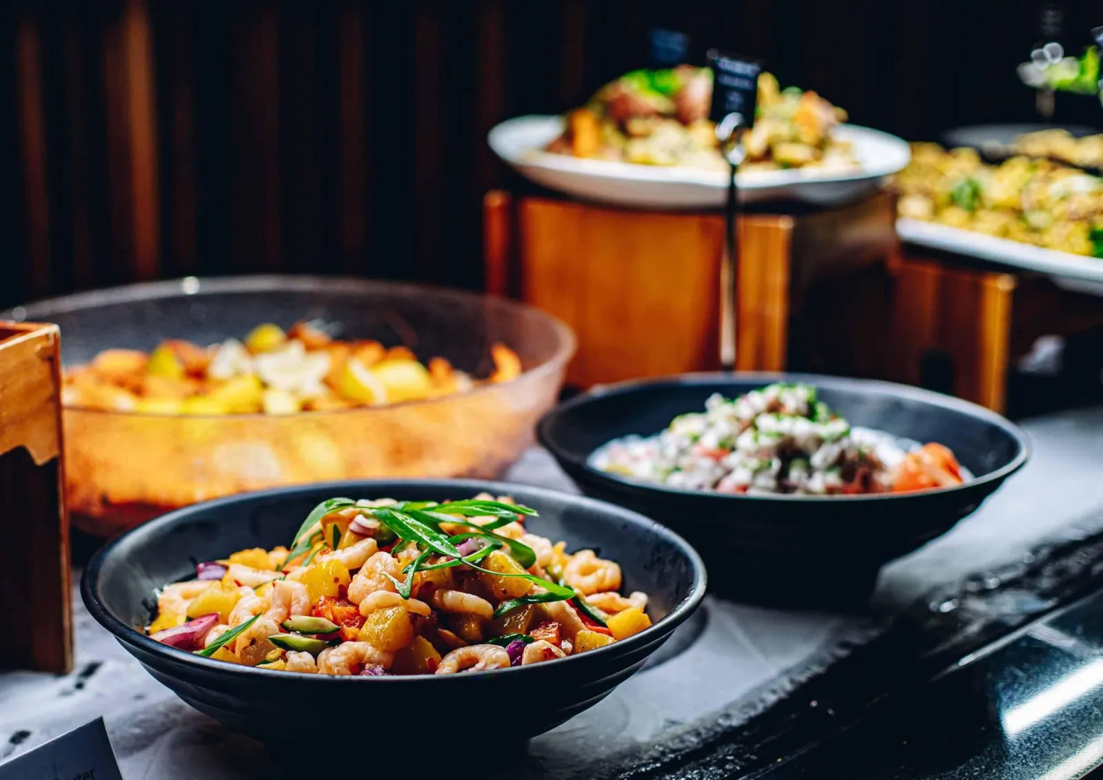 Bowls of hāngī vegetables, seafood and salads laid out on the buffet