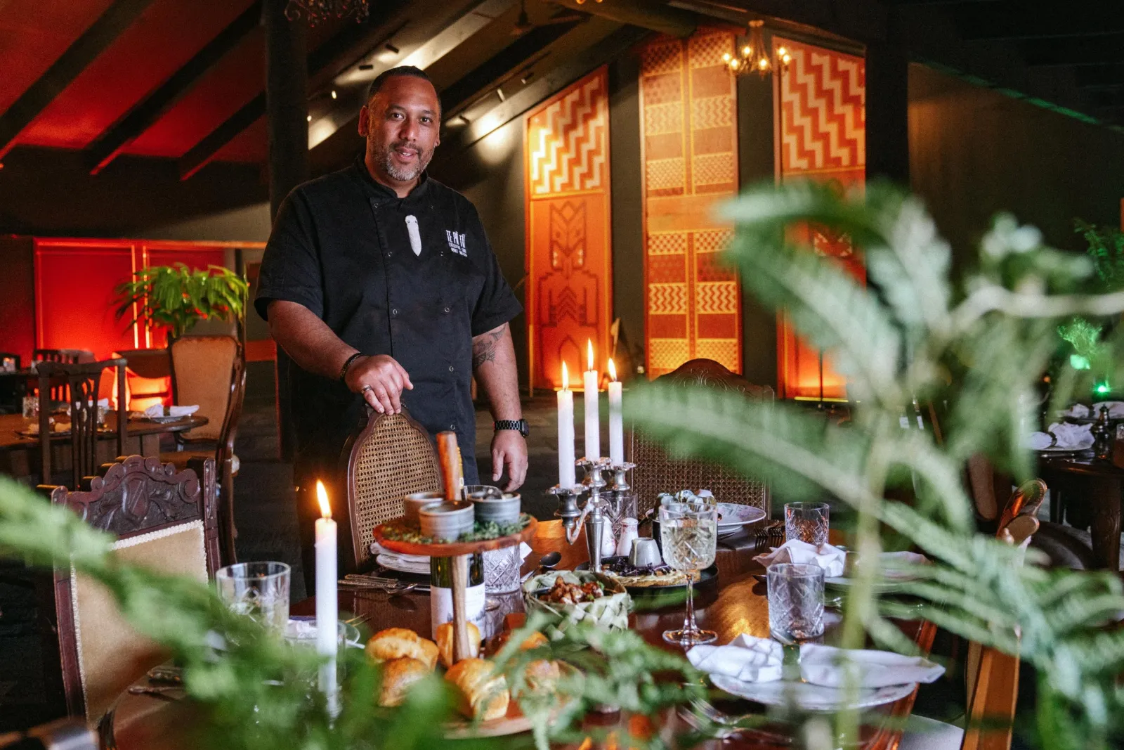 Chef beside a candlelit table set for the four-course dinner at Te Pā Tū