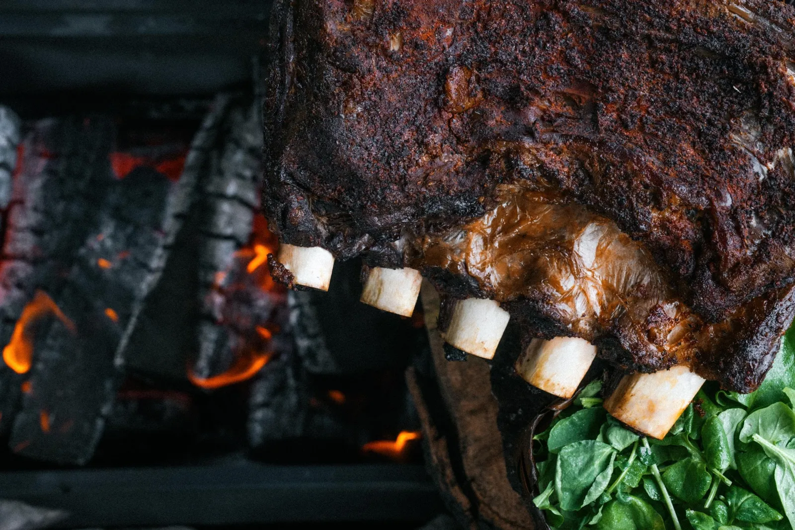 Meat and kūmara roasting over open embers at Te Pā Tū