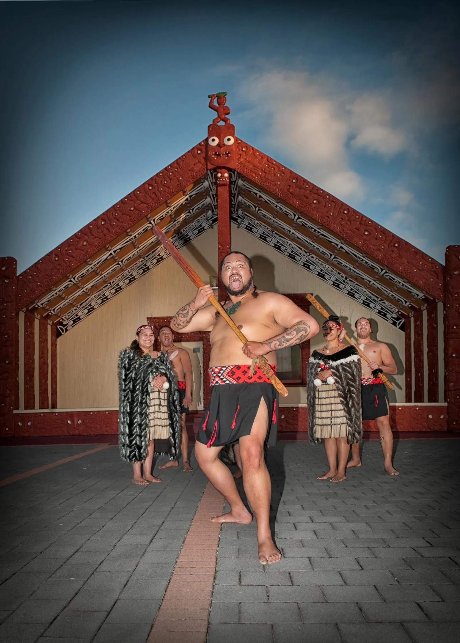 A warrior performing on the marae ātea in front of the carved wharenui
