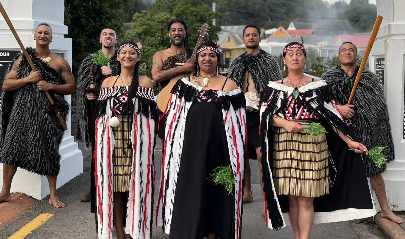 Performers in korowai and piupiu holding taiaha at the village gate